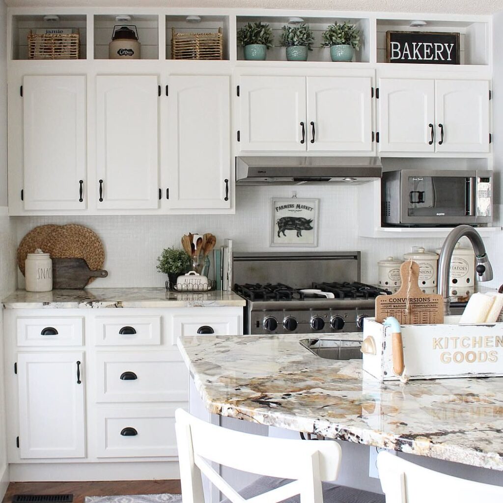 White kitchen cabinets with marble countertops, a stove, and additional open shelving above the upper cabinets.