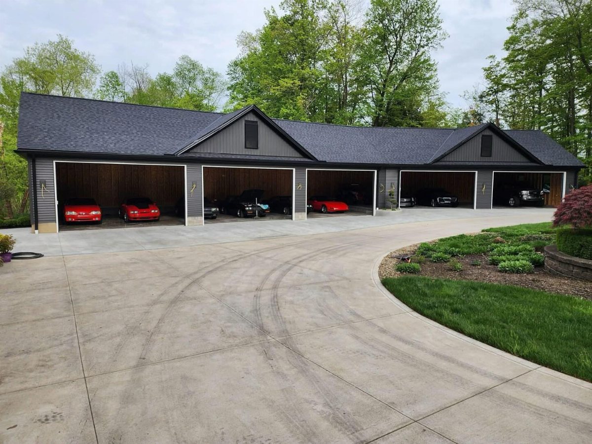 A large multi-bay garage with several cars parked inside under a dark grey roof.