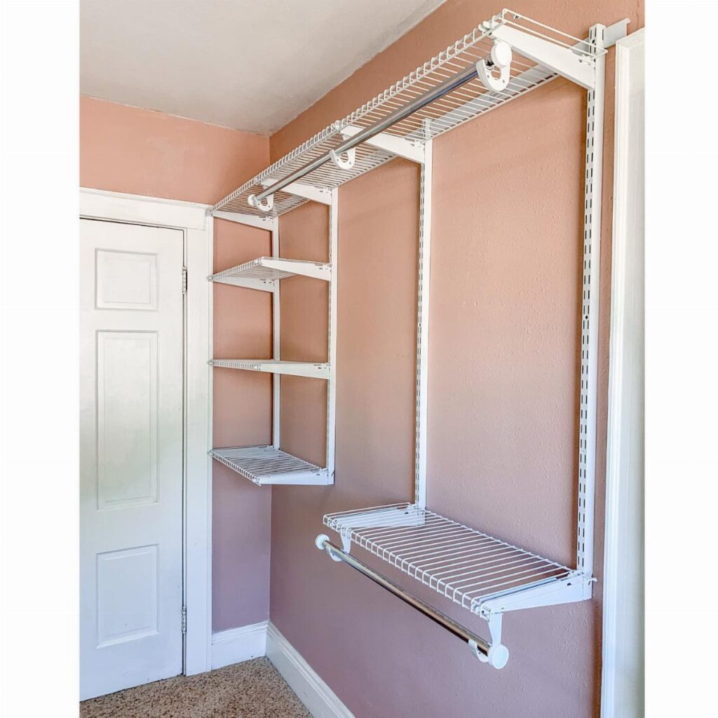 White wire closet organizer system with shelves and hanging rods installed on a peach wall.