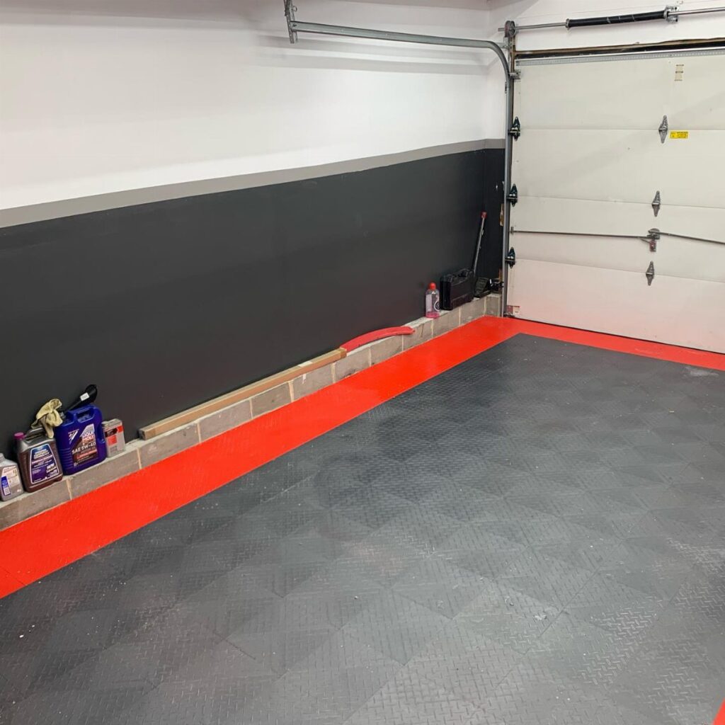 A garage with black and white painted walls and a red and grey floor.