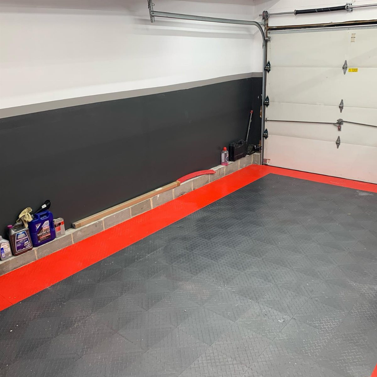A garage with black and white painted walls and a red and grey floor.