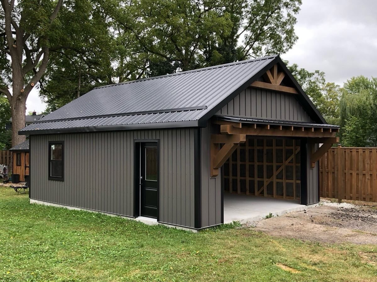 A dark grey metal shed with vertical siding and a large open timber-framed garage area.