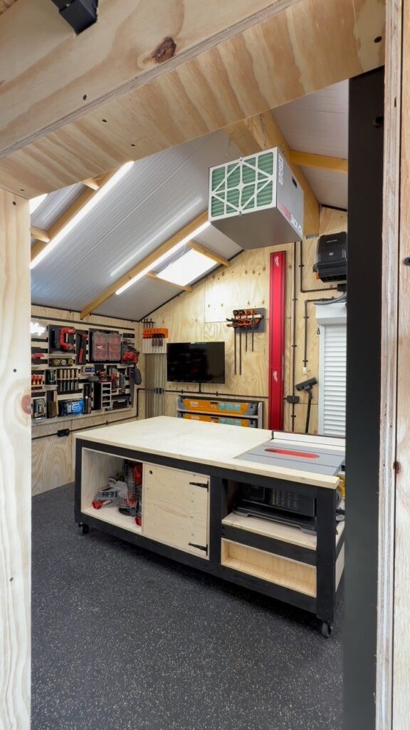 A clean, organized workshop shed with a large workbench and various tools on pegboards.