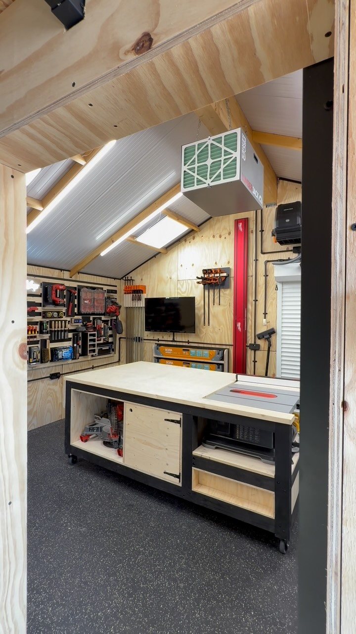 A clean, organized workshop shed with a large workbench and various tools on pegboards.