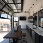 Modern kitchen with a large glass garage door opening onto an outdoor patio and grill.
