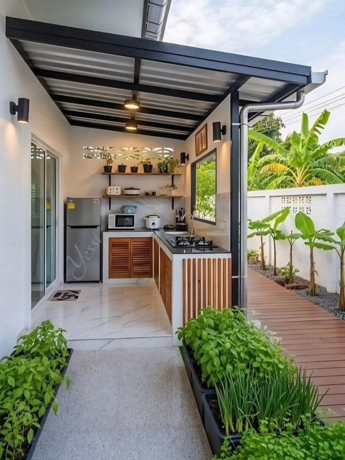 A compact outdoor kitchen with wooden cabinets, a small stove, and greenery under a black awning.